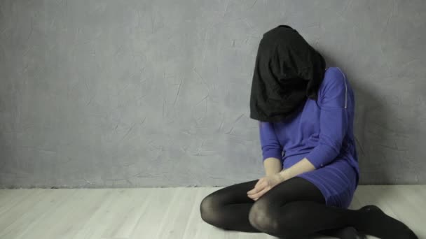 Frightened girl black cloth bag on her head and gagged sits on the floor. kidnapping and violence — Stock Video