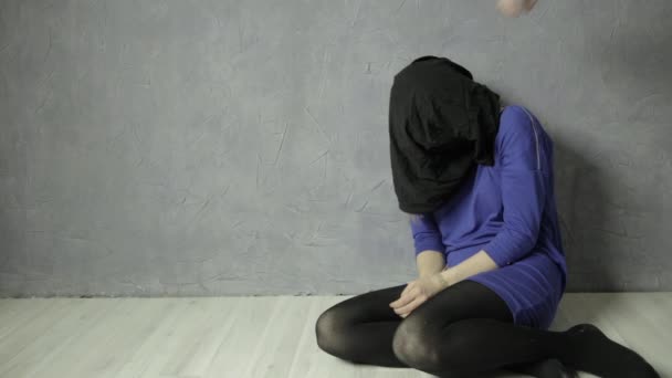 Τρομοκρατημένη κοπέλα μαύρη υφασμάτινη τσάντα της κεφαλής και φιμώνεται κάθεται στο πάτωμα. απαγωγή και βία — Αρχείο Βίντεο