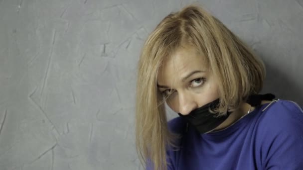 Перелякана дівчина з кляпом у роті сидить на підлозі. викрадення та насильство — стокове відео