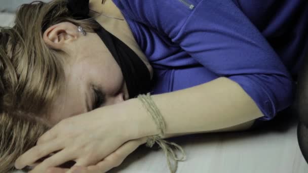 Gritos assustados menina amordaçada, encontra-se no chão com as mãos atadas. rapto e violência — Vídeo de Stock