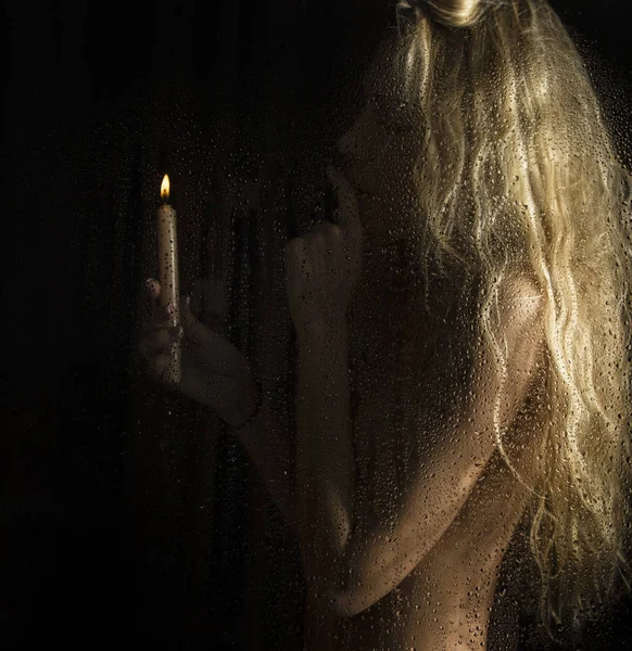 Mujer rubia desnuda rizada con vela sobre fondo oscuro — Foto de Stock