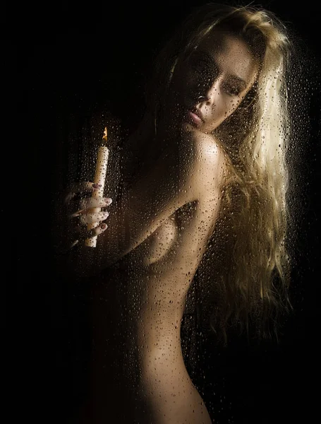 Curly nude blonde woman with candle on dark background — Stock Photo, Image