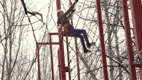 Mladý teenager horolezec chodí přívěsek dřevěný most na vysokých lanových překážek v extrémních parku — Stock video