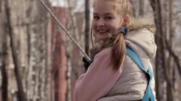 Jeune adolescent grimpeur marche par pendentif pont en rondins sur le parcours de cordes élevées dans le parc extrême — Video
