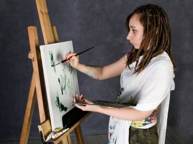 kadın boya sanatçı bir şövale ve boyalar bir tuval üzerine poz tasvir bir Düşler