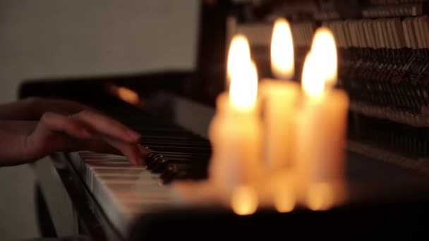 Tangan perempuan close-up bermain piano pada gelap dalam cahaya lilin — Stok Video