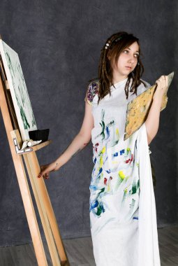 kadın boya sanatçı bir şövale ve boyalar bir tuval üzerine poz tasvir bir Düşler