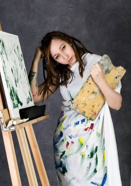 kadın boya sanatçı bir şövale ve boyalar bir tuval üzerine poz tasvir bir Düşler