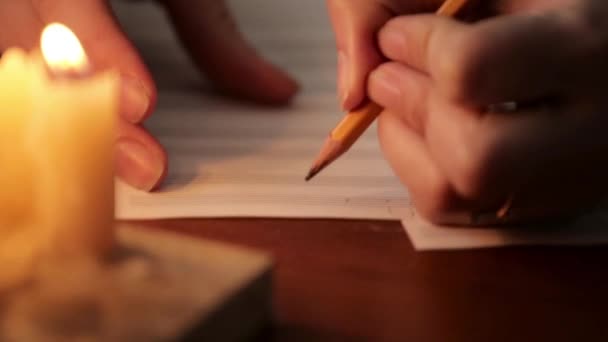 Student skriver en musik: musiker komponera med en blyertspenna i en notbok med levande ljus. närbild av musiker hand — Stockvideo