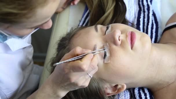 Hermosa mujer joven con extensión de pestañas. Ojo de mujer con pestañas largas. Extensión de pestañas esteticista para mujer joven en un salón de belleza — Vídeos de Stock