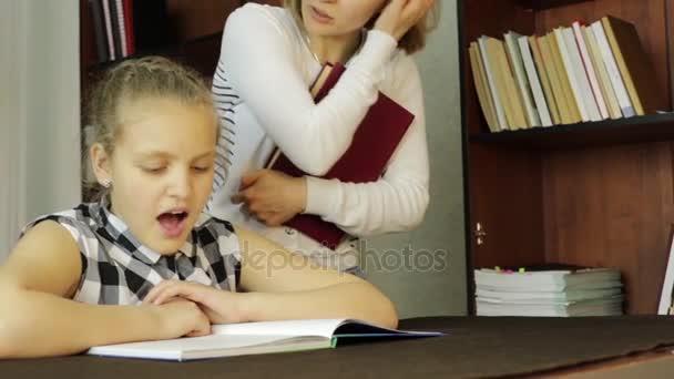 Niña molesta haciendo tareas escolares con la madre, mamá obliga a su hija a leer — Vídeos de Stock