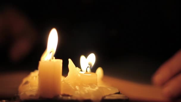 Nahaufnahme Kerzenlicht. Mann beim Lesen und Berühren eines alten Buches. Buch auf einem Schreibtisch im dunklen Raum — Stockvideo