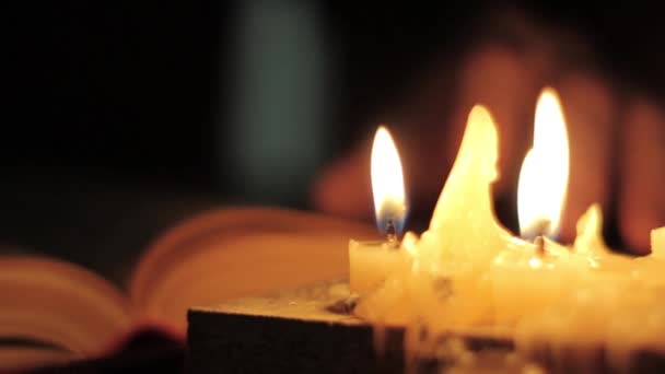 Monge lendo e tocando um amarelo páginas de livro antigo. Luz de vela close-up . — Vídeo de Stock