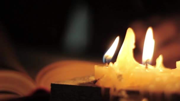 Mönch beim Lesen und Berühren eines alten Buches. Mann bläst Kerzen aus. Buch auf einem Schreibtisch im dunklen Raum — Stockvideo