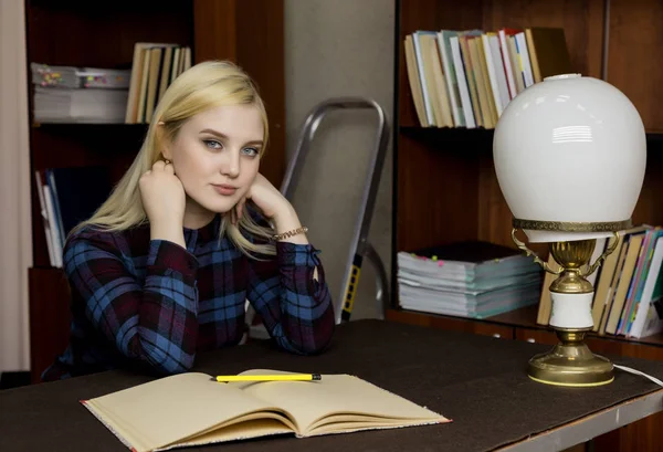 Mladé ženy knihovnice čtení velké knihy v knihovně. regály s knihami, schůdky a stůl s lampou — Stock fotografie