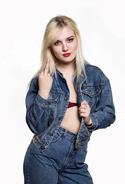 Sporty girl in denim jaket and jeans show middle finger, fuck you off sign on white background. indecent lifestyle concept — Stock Photo, Image
