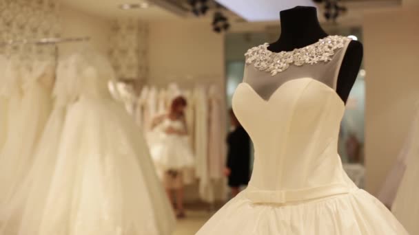 ウェディング ドレスとダミーのクローズ アップ。店員はかなり若い女性の結婚式のガウンを選択する助けています。背景のボケ. — ストック動画