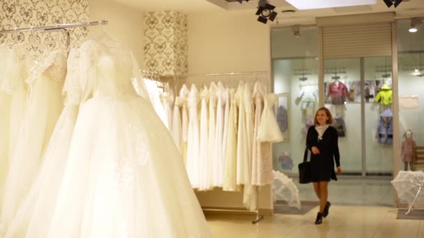 Bela noiva jovem escolher um vestido de noiva em uma boutique de casamento . — Vídeo de Stock