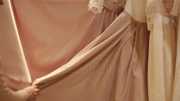 Красивая молодая женщина выбирает свадебное платье. Помощник продавца помогает девушкам в свадебном магазине . — стоковое видео