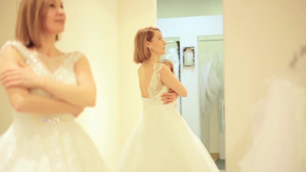 Elegante Braut probiert Hochzeitskleid im Brautladen in Umkleidekabine — Stockvideo