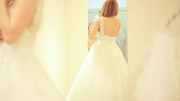 Элегантная невеста примеряет свадебное платье в свадебном магазине в примерочной — стоковое видео