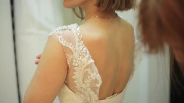 花嫁介添人がひもを結んで美しい yaung 女性ブライダル ブティックでは、結婚式の準備の概念のためのウェディング ドレス — ストック動画