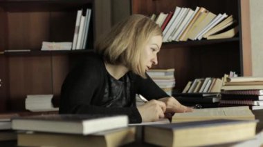 Masada oturan kız öğrenci ve gerekli bilgi kitap yazıyor