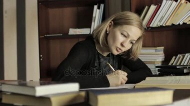 Öğrenci üniversite kitaplığında sınavlarına hazırlık odaklı.