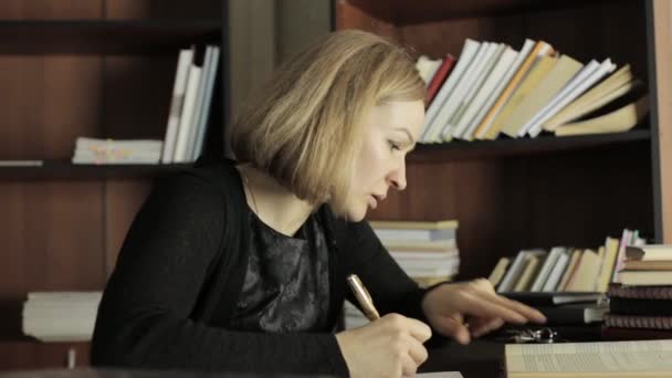 Fokuserad student som studerar i biblioteket i college. Kvinnlig student sitter vid skrivbordet och göra läxor — Stockvideo