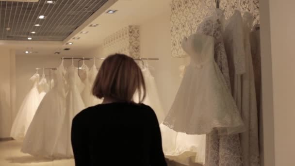 Giovane bella donna che sceglie un abito bianco in un negozio di nozze. Concetto di mercoledì — Video Stock