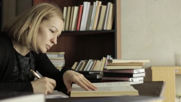 Focused female student working with books in a library in university college. tired student preparing for exams — Stock Video