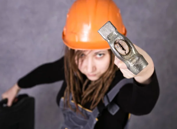 Niña en casco de seguridad chaleco naranja que sostiene la herramienta de martillo — Foto de Stock