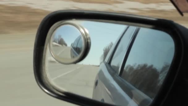 Задній шлях відображається в дзеркалі автомобіля, автомобіль швидко їде на автостраді — стокове відео