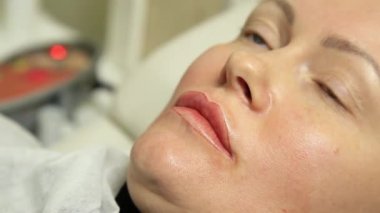 Genç güzel kadın Başlarken dudak dövme. kalıcı makyaj dudaklar Güzellik Salonu