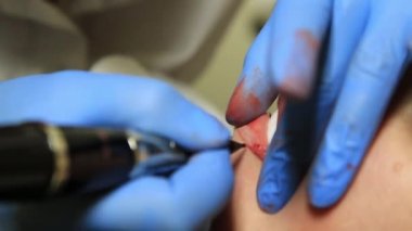 Genç güzel kadın Başlarken dudak dövme. kalıcı makyaj dudaklar Güzellik Salonu