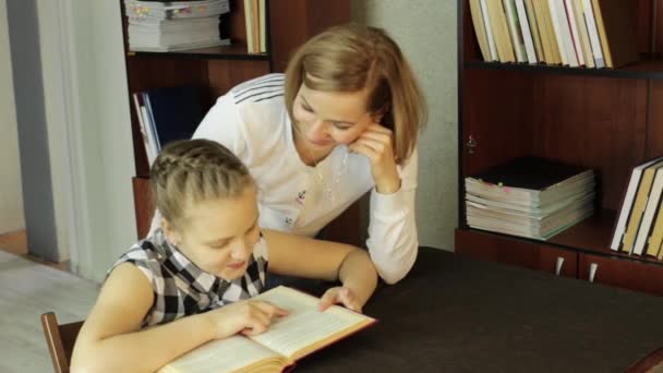 Mamá ayudando a su hija a hacer la tarea. colegiala hace lecciones — Vídeos de Stock