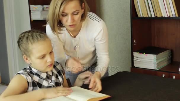 Mamá ayudando a su hija a hacer la tarea. colegiala hace lecciones — Vídeos de Stock