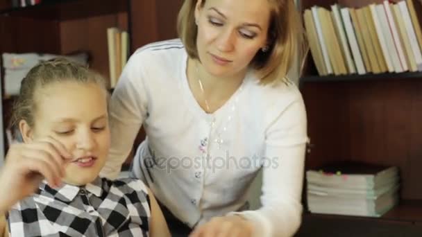 Mamá ayudando a su hija a hacer la tarea. colegiala hace lecciones — Vídeos de Stock