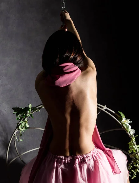 Sexy chica elegancia en una falda rosa, balanceándose en un columpio de metal. aferrarse a cadenas —  Fotos de Stock