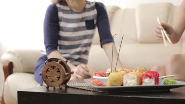 Two girlfriends talking during dinner at the restaurant, eating rolls with chopsticks — Stock Video