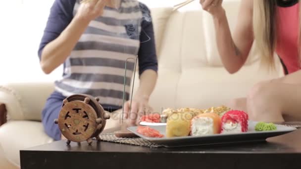 Zwei Freundinnen füttern einander beim Abendessen im Restaurant, essen Semmeln mit Stäbchen — Stockvideo