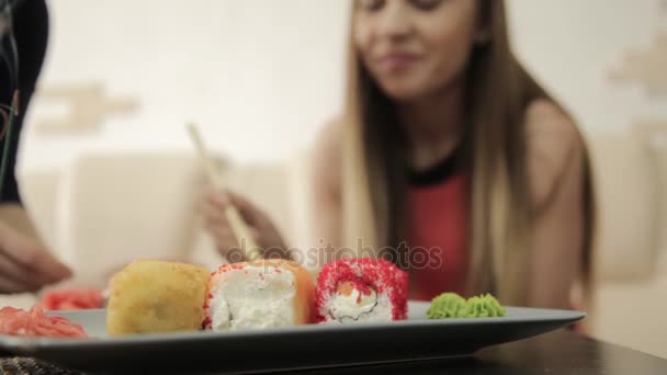 Two girlfriends talking during dinner at the restaurant, eating rolls with chopsticks — Stock Video