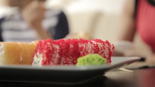 Två flickvänner äta rullar med pinnar under middagen på restaurangen. närbild japanska köket — Stockvideo