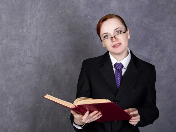 Avvocato donna che tiene un grande libro con espressione seria, donna in completo da uomo, cravatta e occhiali — Foto Stock