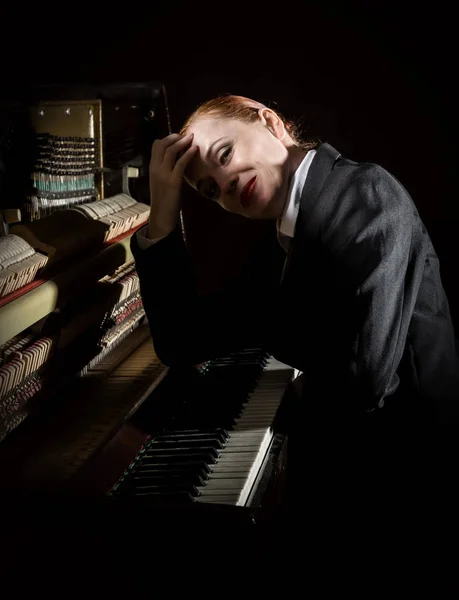 Músico feminino vestido com um terno de homem sentado ao lado do piano — Fotografia de Stock