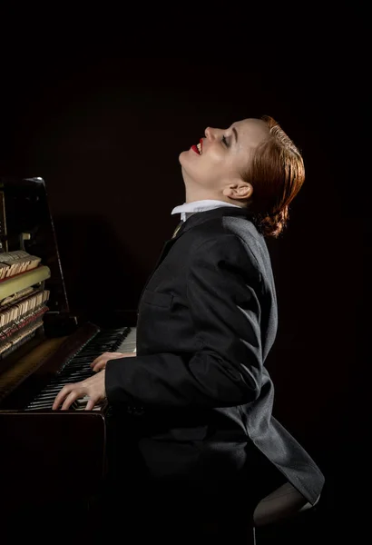 Női zenész öltözött egy mans ruha ül a zongora — Stock Fotó