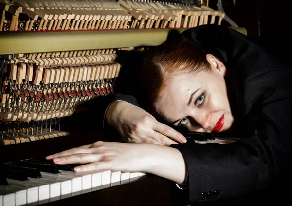 Musicienne vêtue d'un costume mans repose sur un clavier piano — Photo