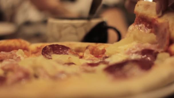 Close-up hand cuts and eats a slice of pizza in a cafe — Stock Video