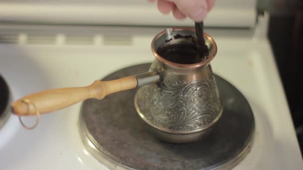 Brew coffee on an electric stove, stirring with a spoon — Stock Video