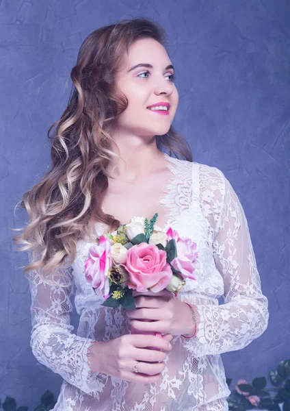 Schöne Mädchen in einem weißen peignoir mit einem Strauß Blumen — Stockfoto